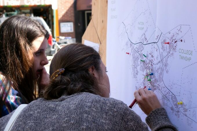 Two students sketching on a map of College Township that was part of the annual nationwide ParkingDay landscape architecture event.