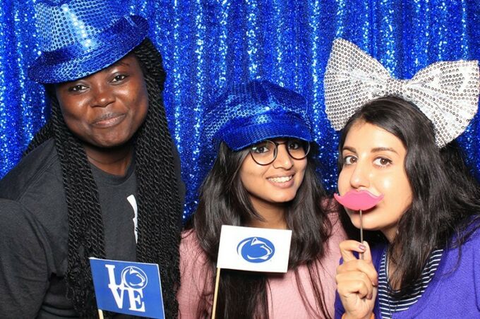 Students pose at the photo booth during Stuckeman's fall welcome back event. Standing in front of a sparkling blue curtain, students can choose fun and silly props to pose with.