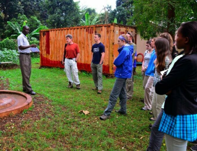 student group listens to Tanzanian man outdoors