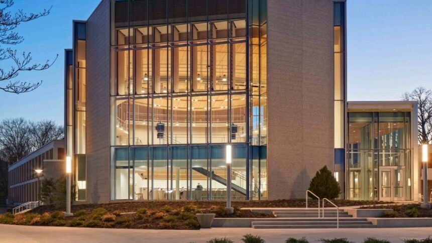 The modern glass facade of Esber Recital Hall illuminating an evening on University Park campus.