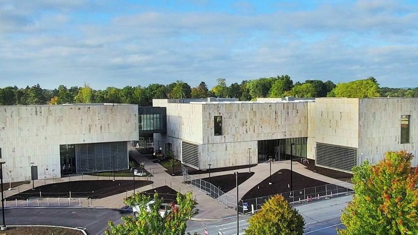 Exterior construction facade of the new palmer museum of art surrounded by trees and a blue sky.