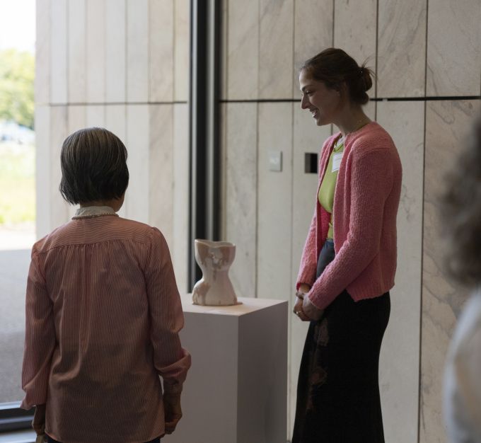 Two event attendees standing next to a sculpture.