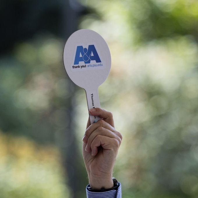 A hand holding up an A&A-branded paddle.