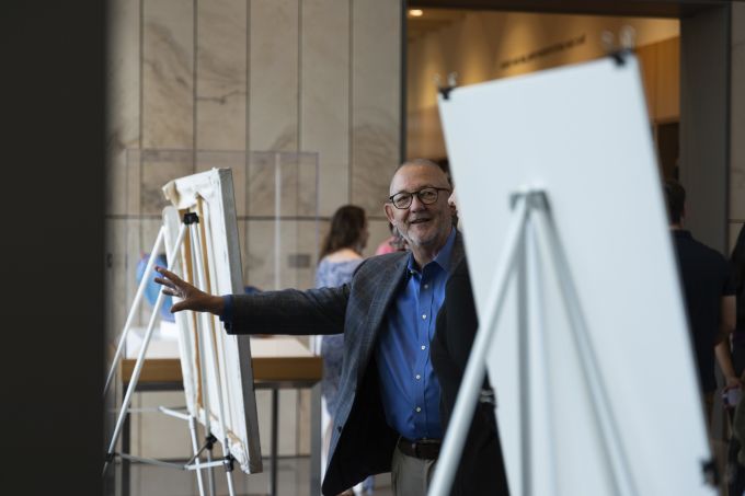 A man standing next to displays while talking to other attendees.