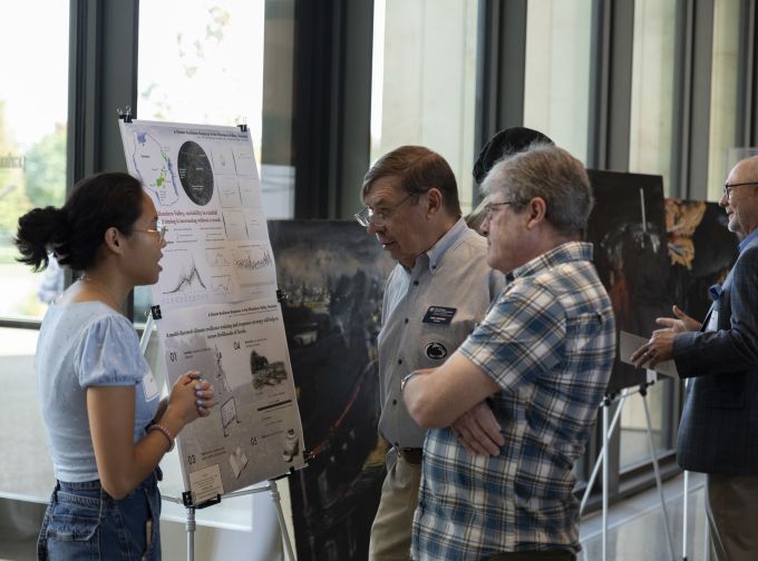 Two donor attendees chatting with an A&A student about her work.