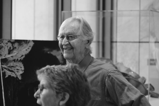 An elderly man smiling and looking onward, standing behind Kimberly Schenck.