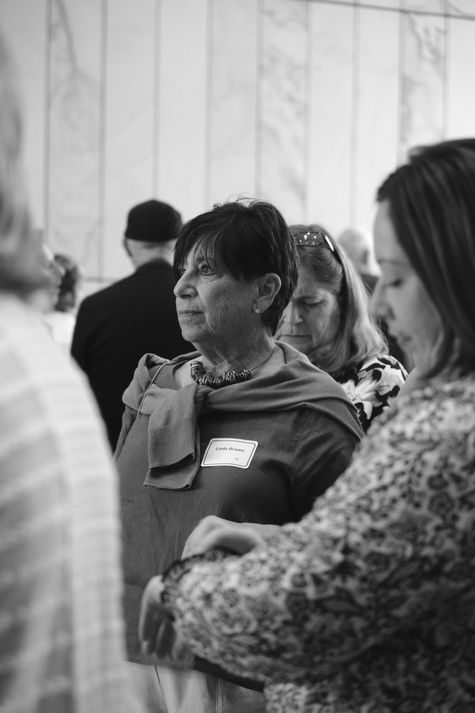 Linda Brown looking off to the left, standing among other attendees.