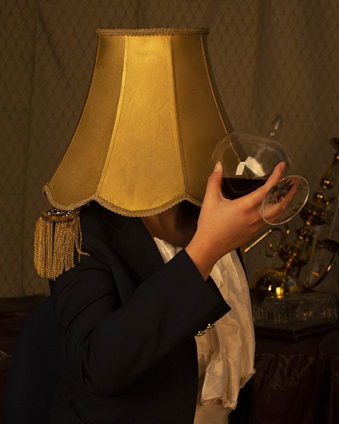 A photograph of a person's arm holding a drink in front of a lamp.