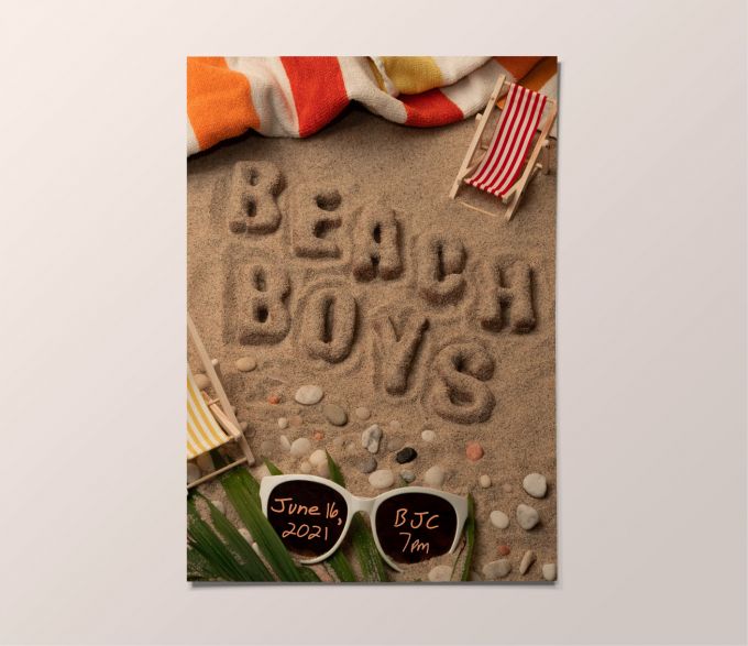 A poster for a Beach Boys concert with the name of the band written in raised sand letters on a beach.