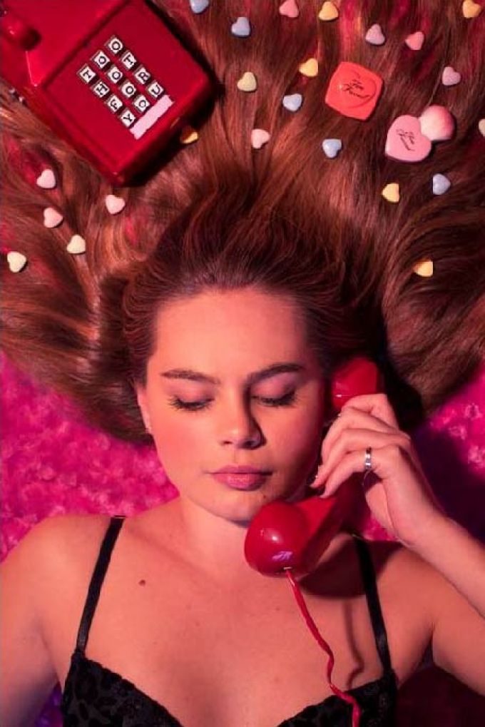 A poster with a closeup of a woman on a red telephone.