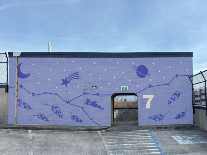 A purple outer space themed mural on the seventh floor of a parking garage.