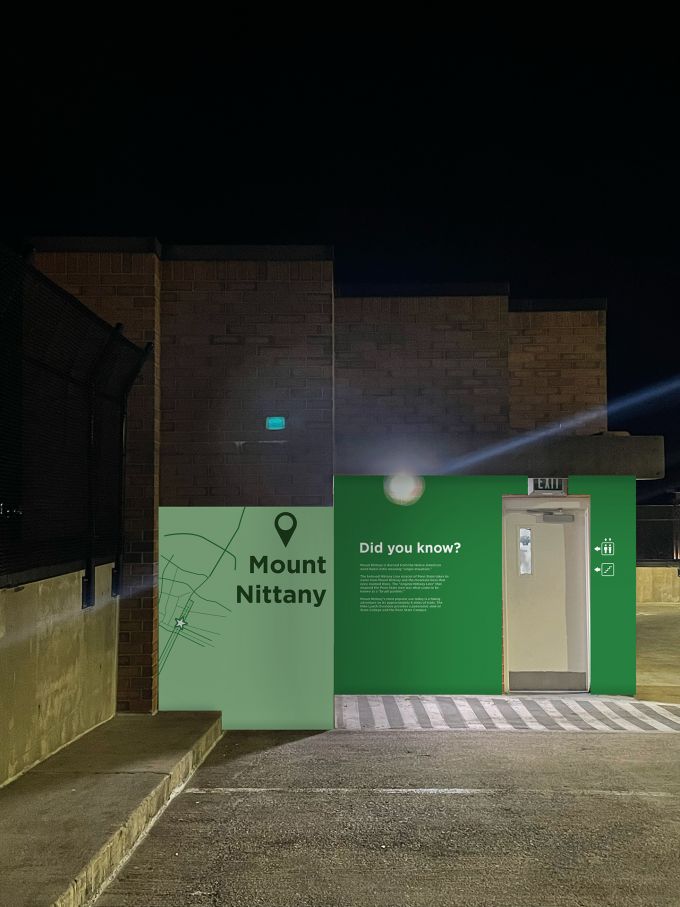 Green branding wall on an inside wall of a parking garage that lists facts about Mount Nittany