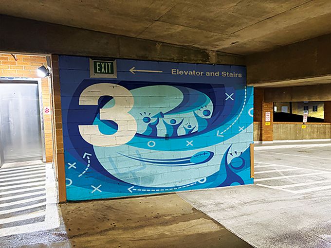 A blue mural painted on the third floor of a parking garage.