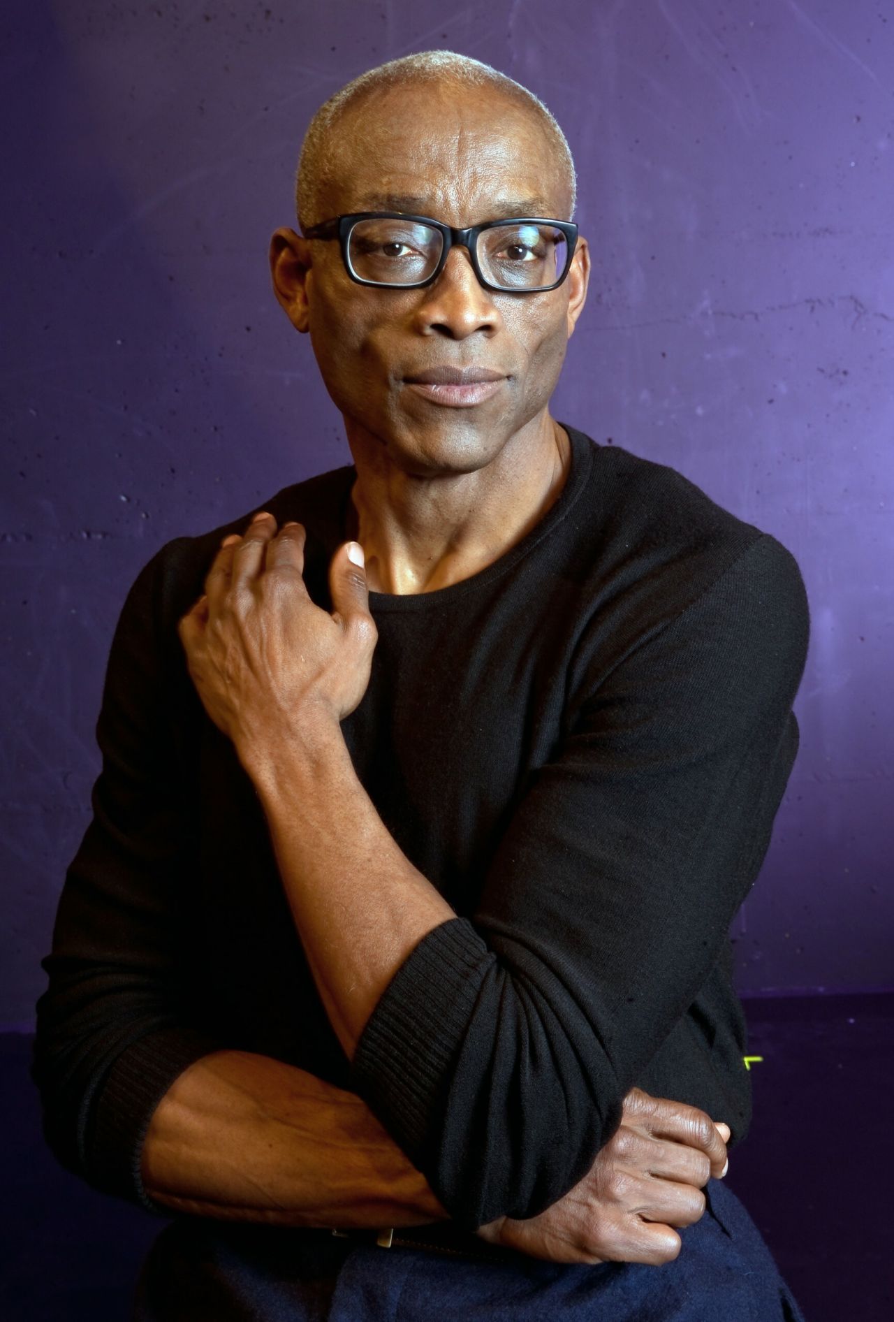 A man crosses his arms and looks at the camera.