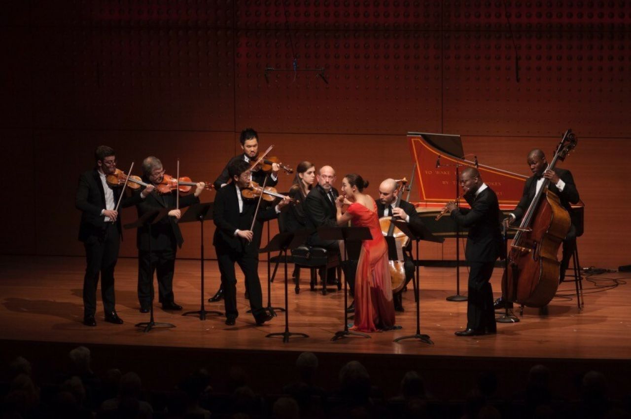 A group of formally dressed musicians perform on their classical instruments.