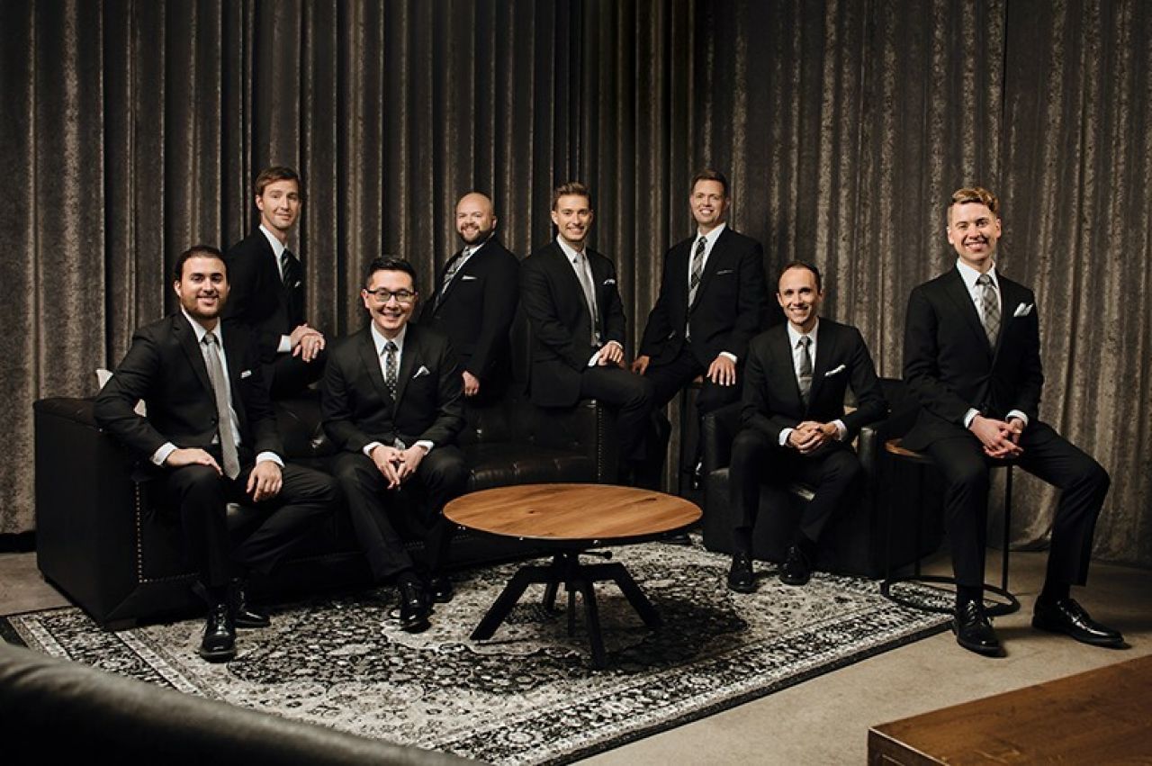 A group of men gather on and around a couch.