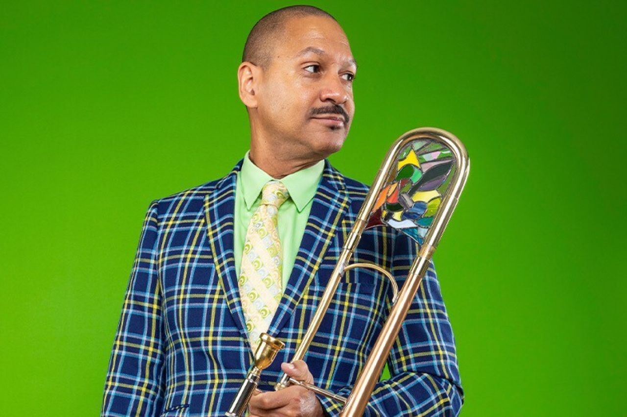 A man holds a trumpet and looks to the side.