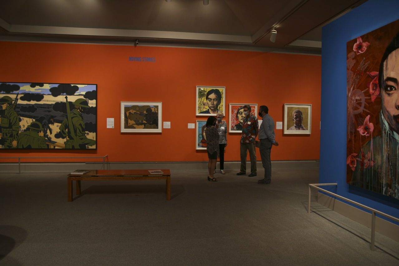 Three people in conversation with each other in an art gallery.