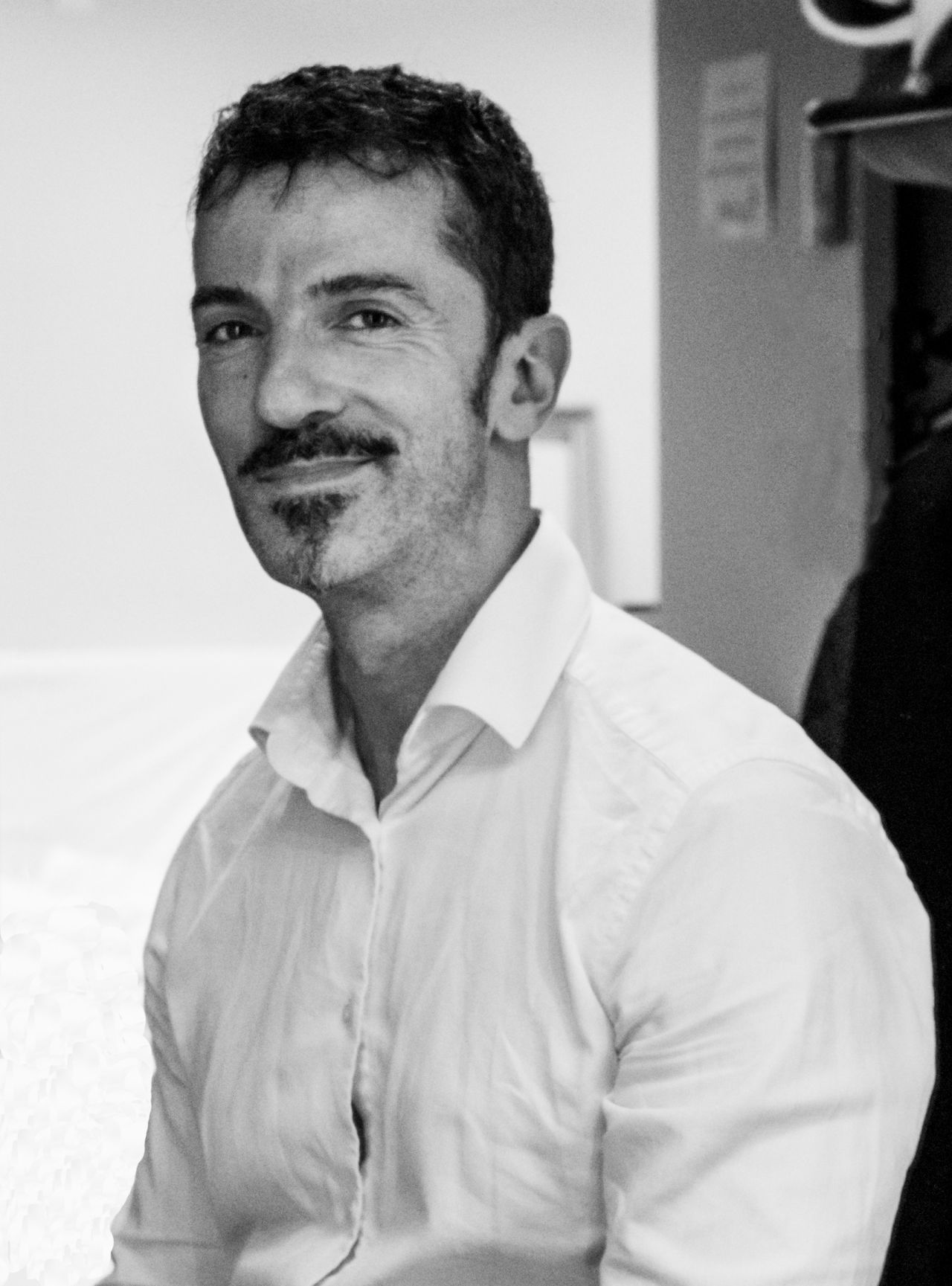 A man with dark hair and a goatee smiles for the camera.