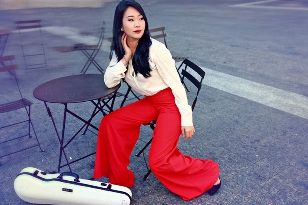 A woman sitting at a small table looks off to her left.