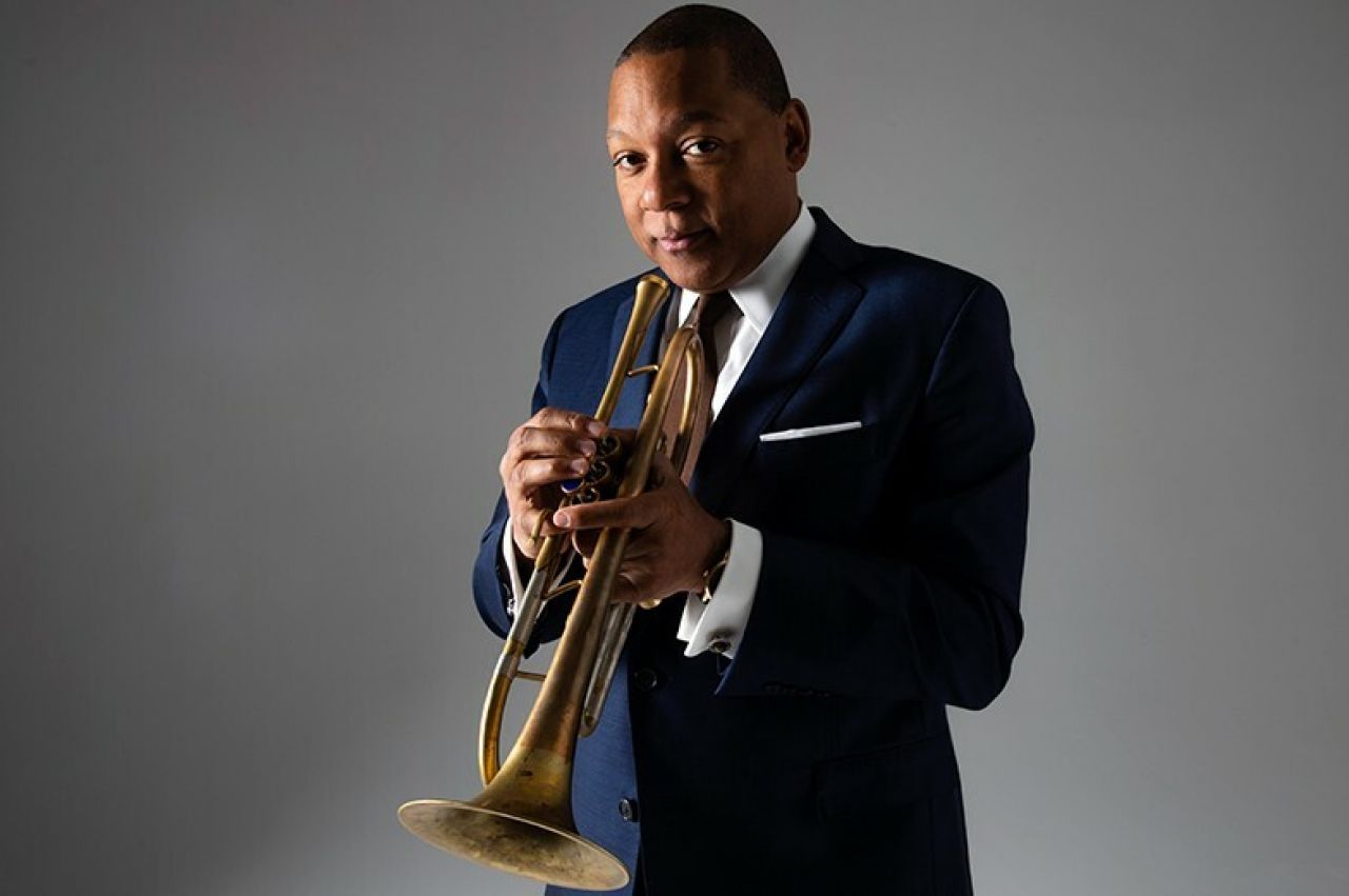 A man stands and holds a trumpet.