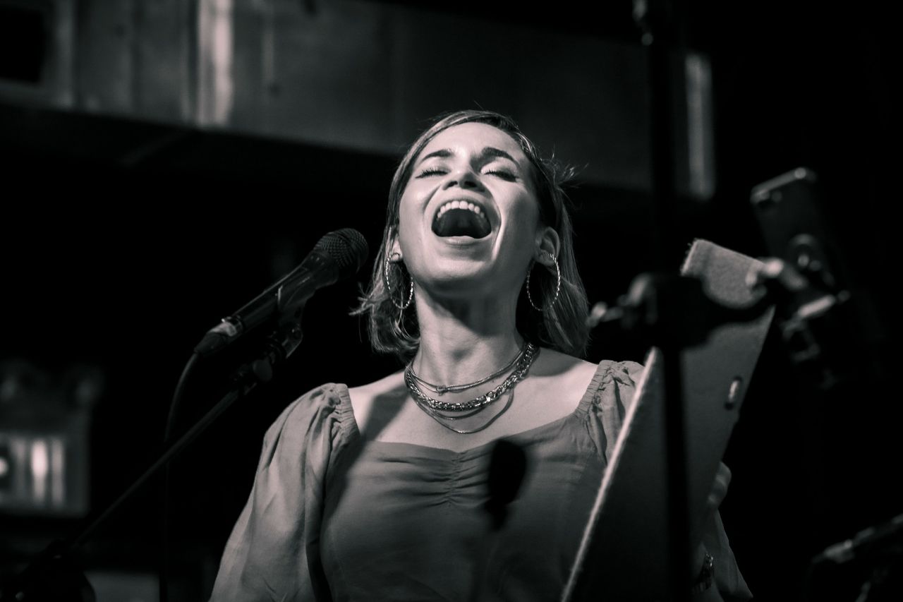 A woman closes her eyes and sings.