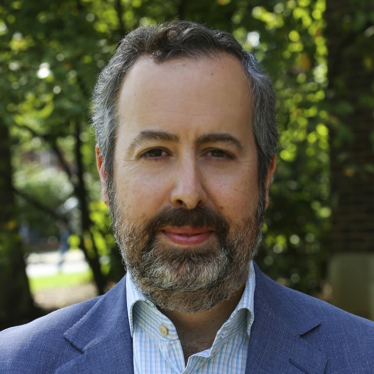Headshot of Professor Robin Thomas wearing plan shirt and blue jacket