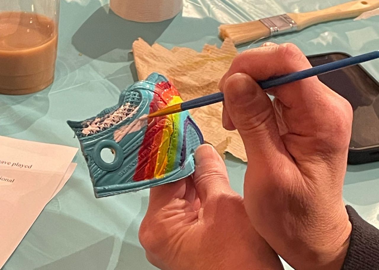 An image shows hands painting a panel of a sneaker.