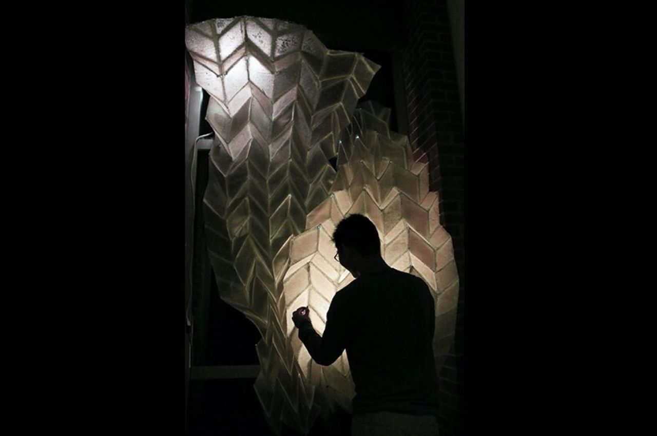 The silhouette of a person against knitted material that has been backlit.