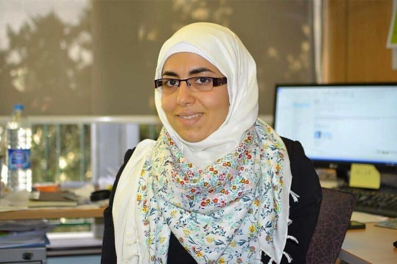 A photo of Dima Abu-Aridah in a headscarf, sitting in front of a computer.