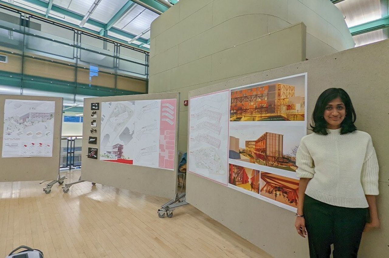 Anjali Gopalakrishnan stands next to pinup boards featuring her architectural renderings.