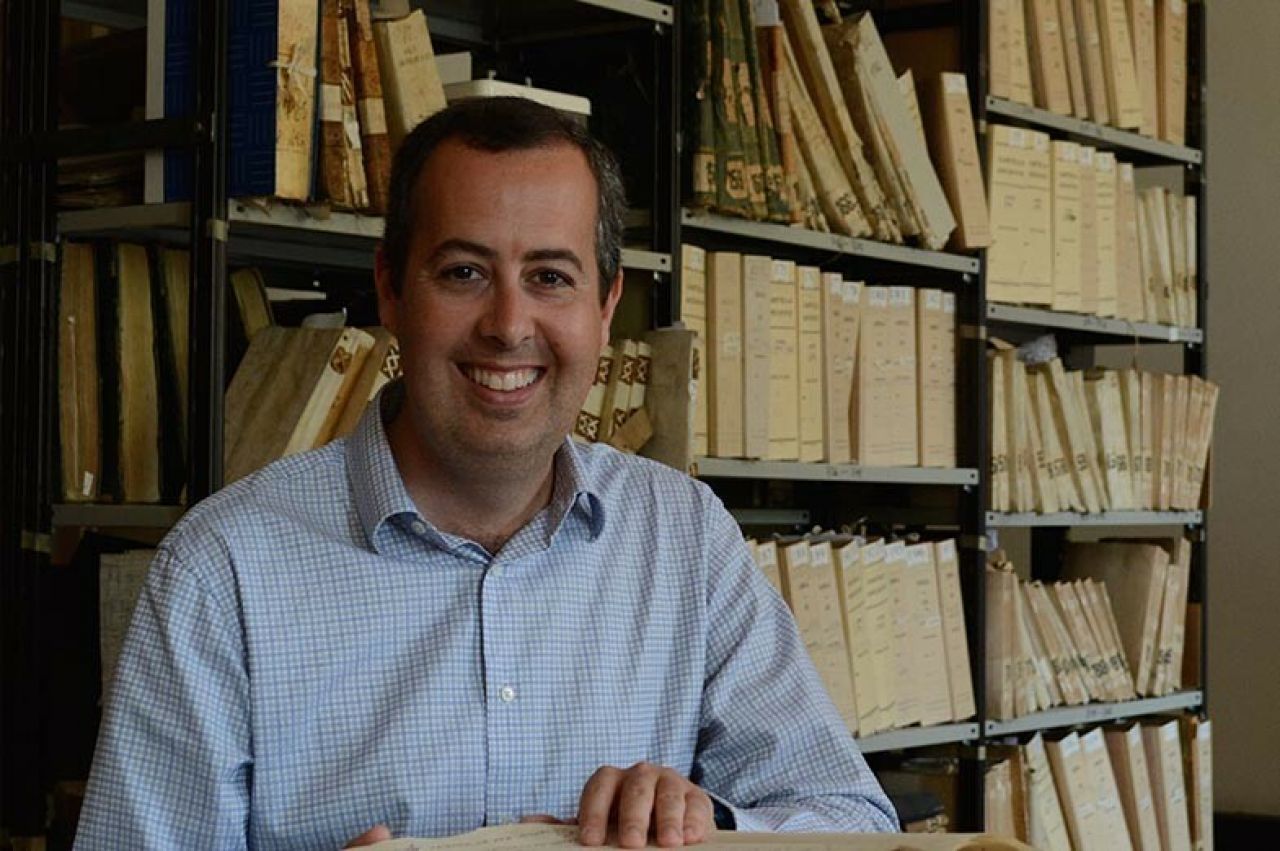 Headshot of Robin Thomas with archive of books in the background.