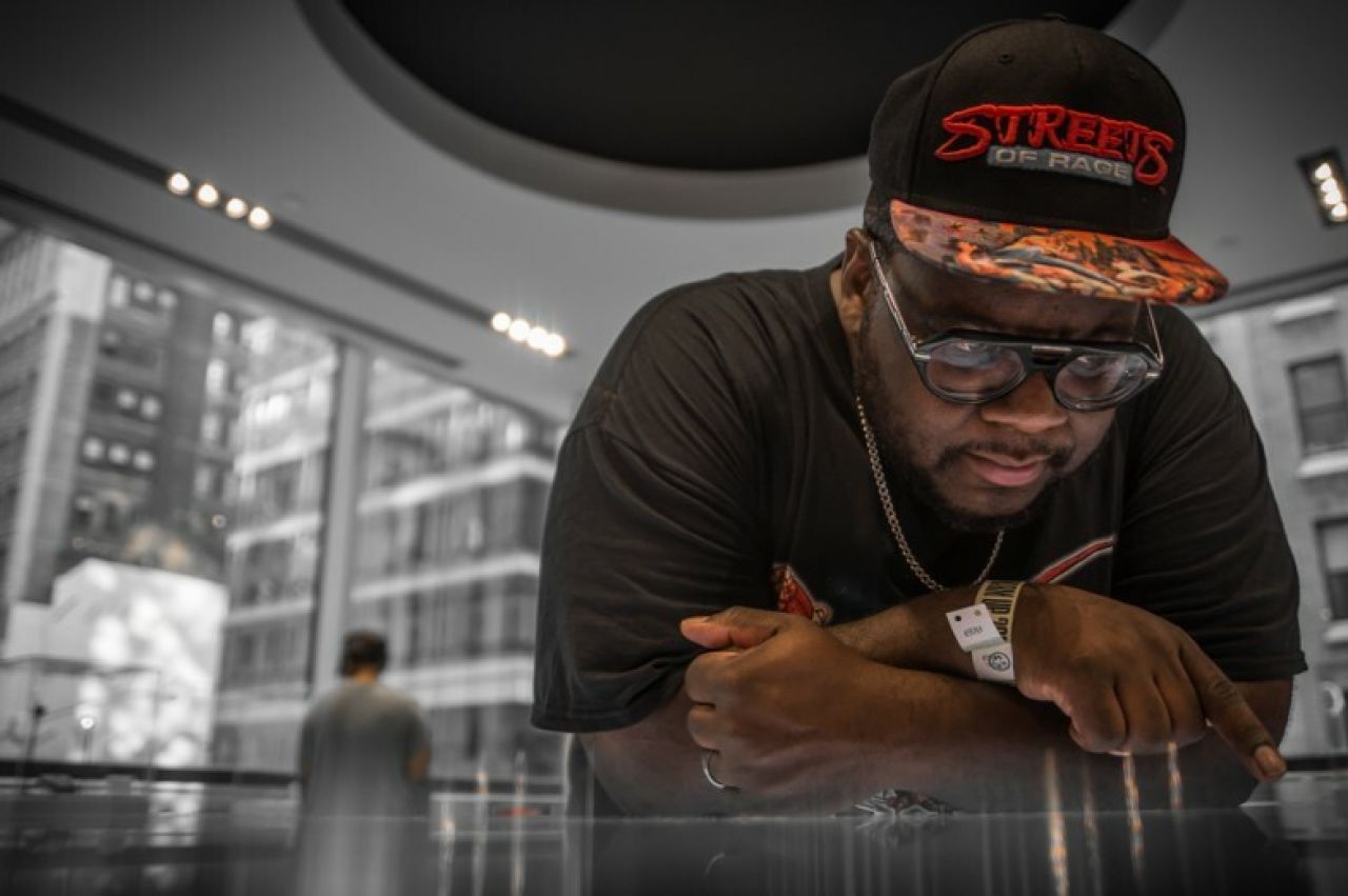 Penn State alumnus Raheem Jarbo, who performs as MegaRan, leaning on a reflective table.