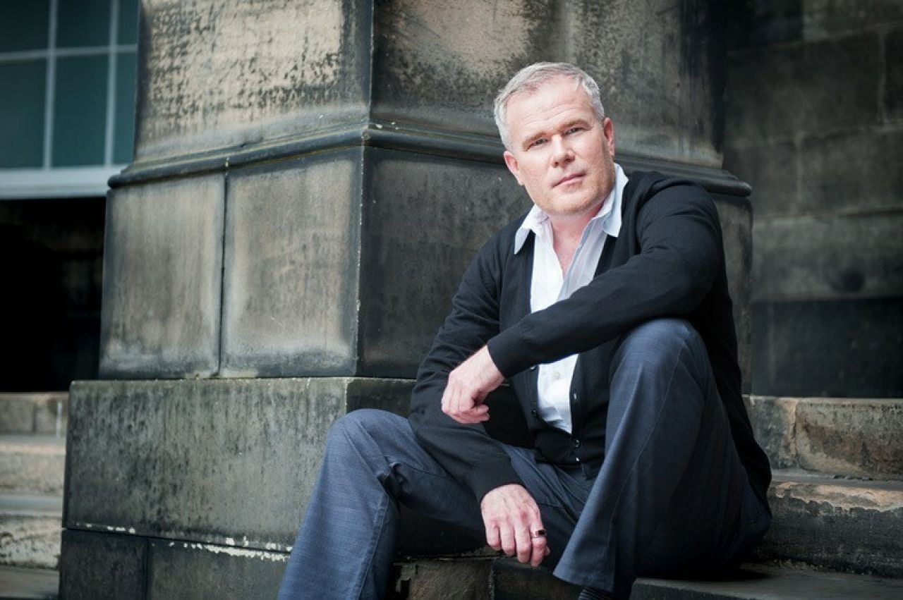 A photograph of Paul Daniel Marriott sitting on the steps of a building.