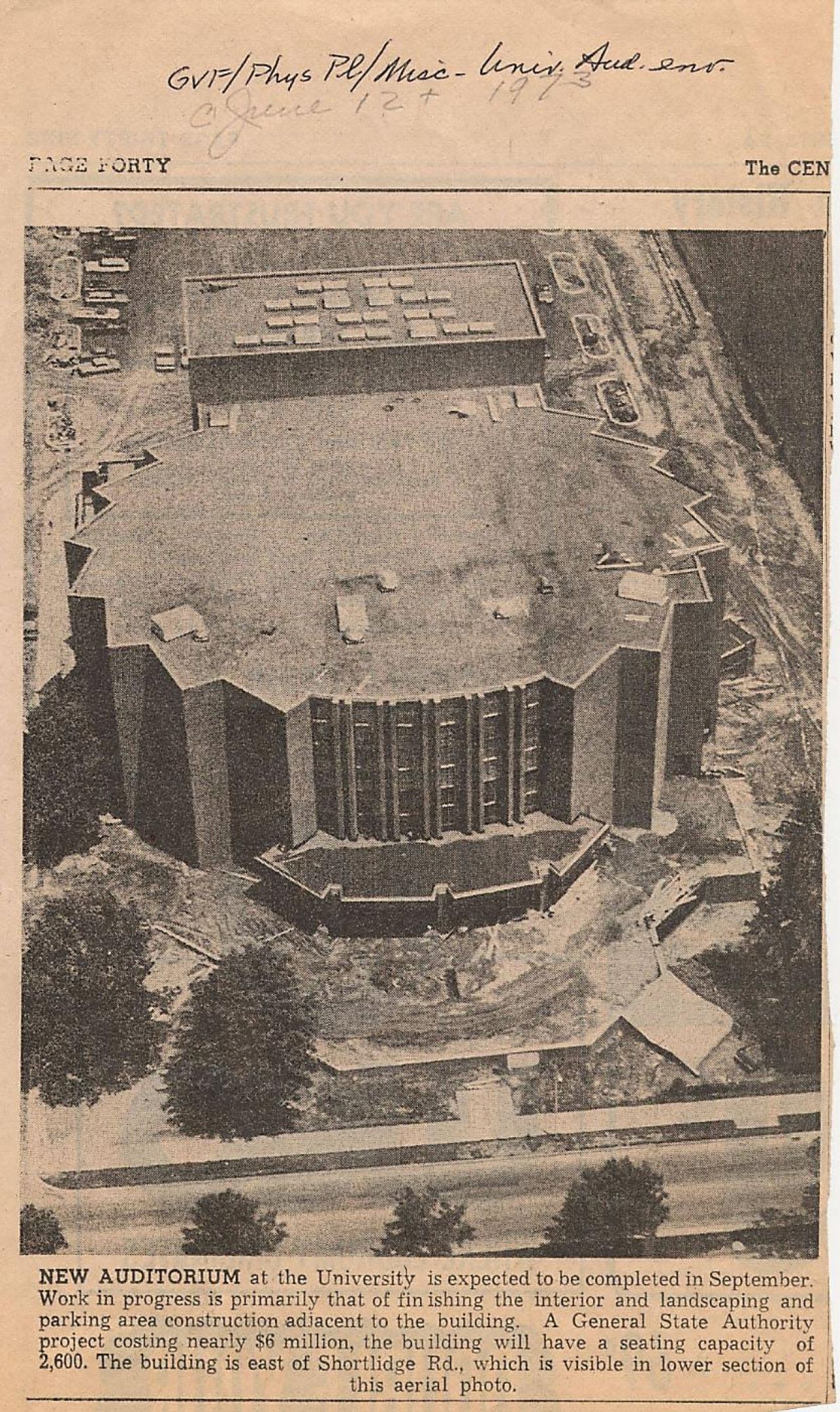 An archival newspaper clipping shows a bird's-eye view of a large brick building.