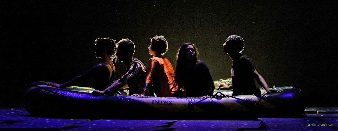 A group of four people sit in an inflatable raft.