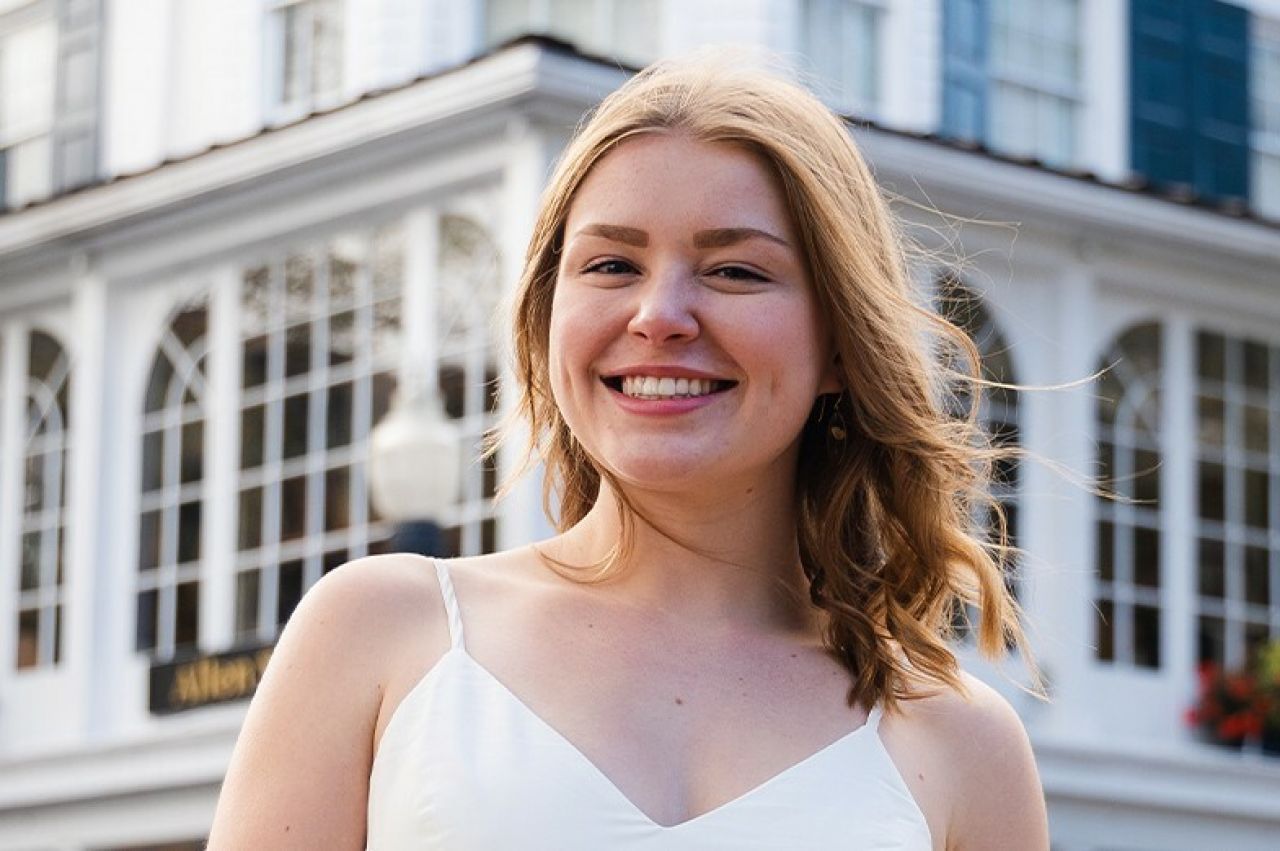 Red-haired young woman with white dress smiling outside