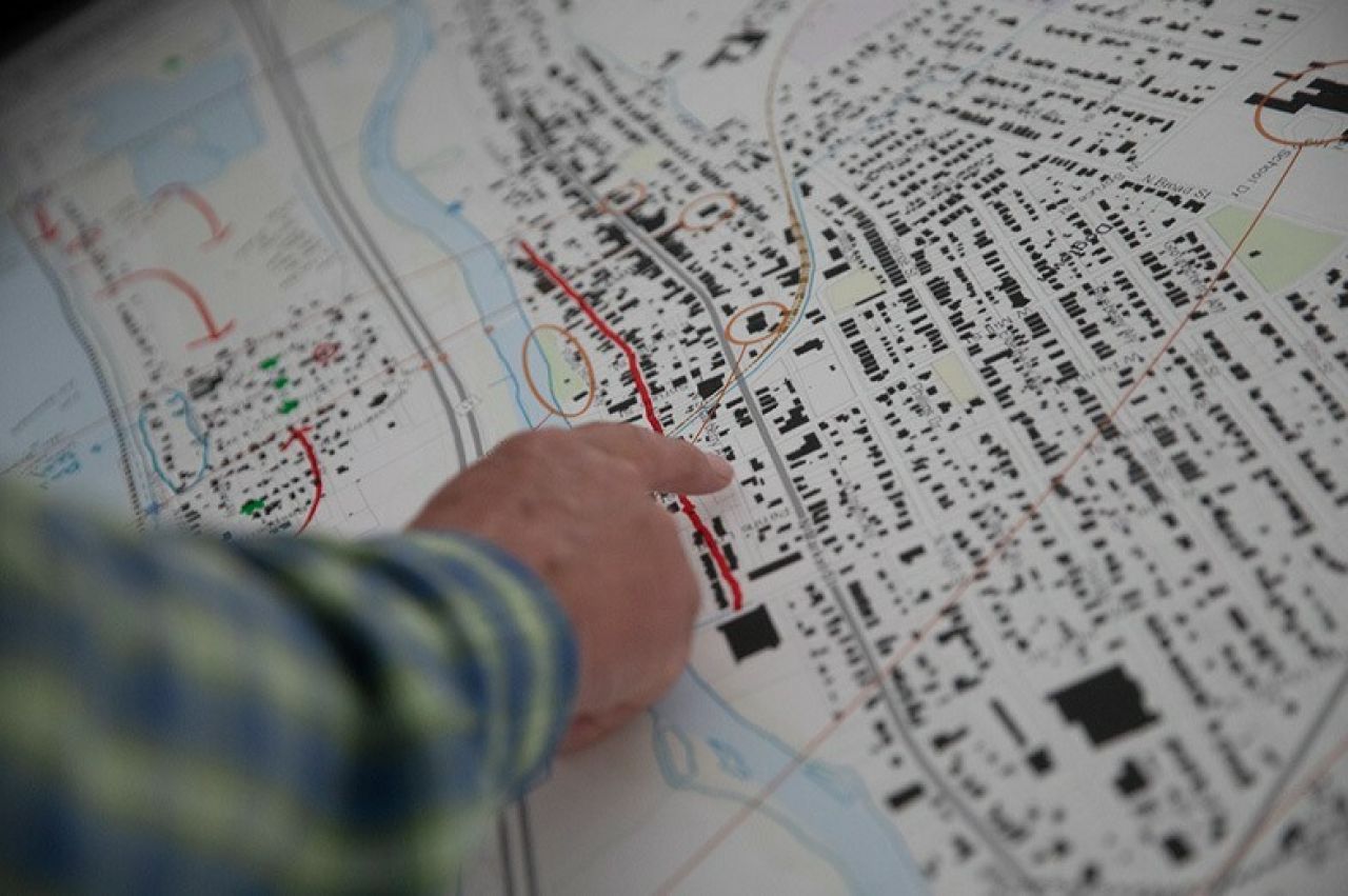 A close up photo of a man's hand pointing at a map showing housing clusters,