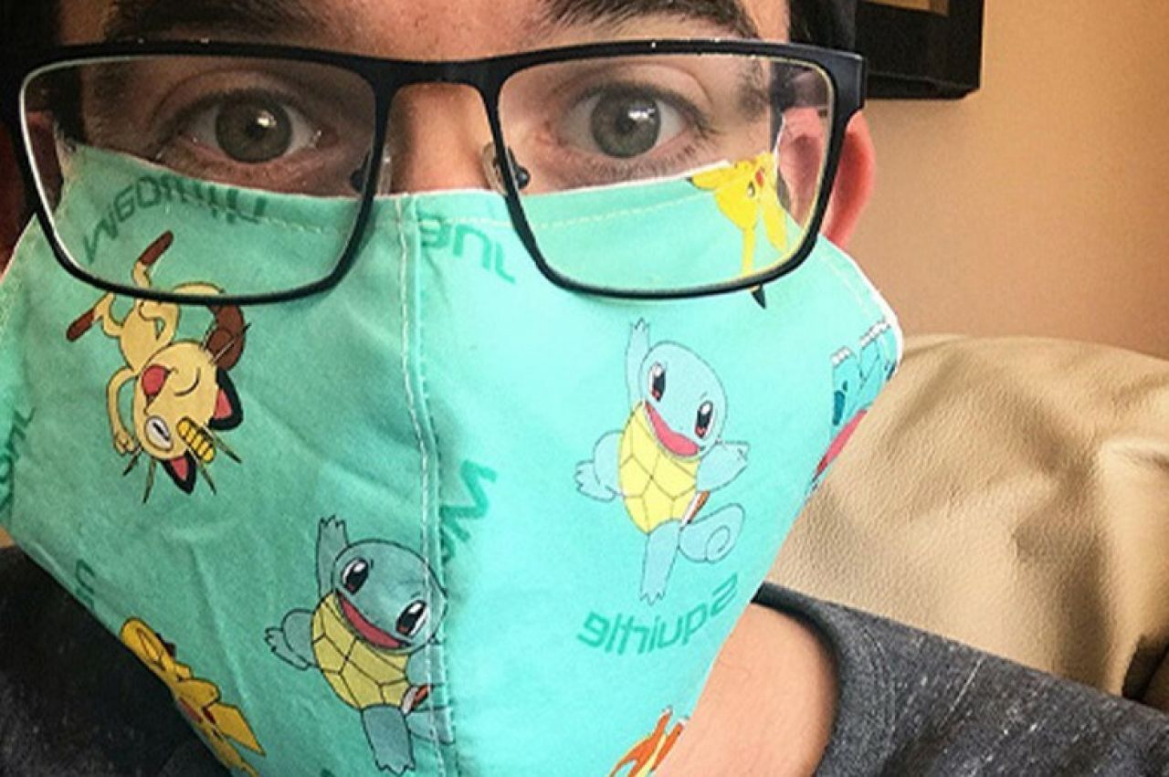 man with dark rimmed glasses posing with a Pokemon-themed mask
