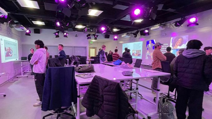 Students looking at large screens in a technology classroom