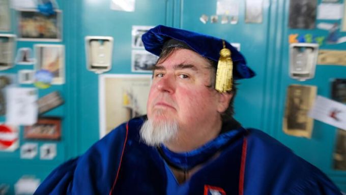 Selfie of an older white man wearing blue commencement regalia