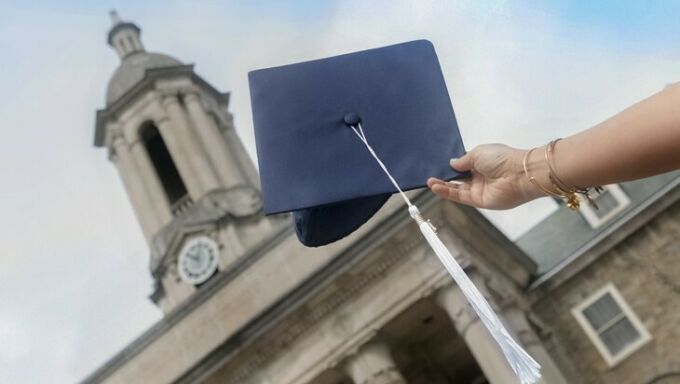 A mortarboard held up in front of Old Main