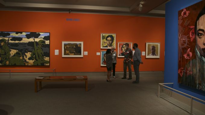 Three people in conversation with each other in an art gallery.