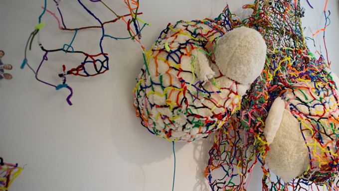 3-D art installation with stuffed animal-like object wrapped in multicolored thread