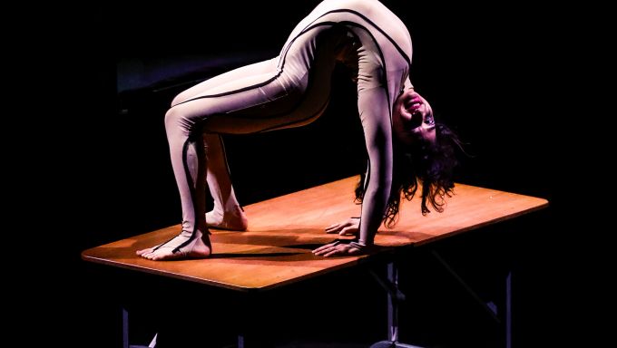 An acrobat bends over backwards on a portable table.