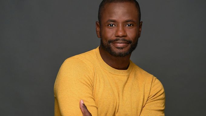 Young black man with yellow sweater and arms crossed