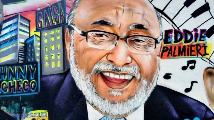 A spray-painted wall mural depicts Latin jazz musician Eddie Palmieri in bold colors.