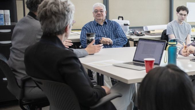 A man sitting at a table listening to the others around the table.