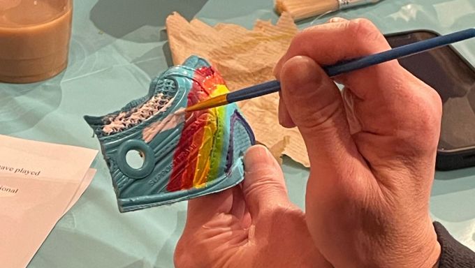 An image shows hands painting a panel of a sneaker.