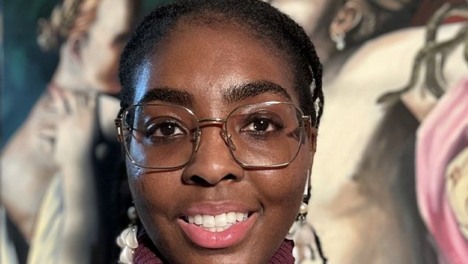 Headshot of a young Black woman with glasses smiling.